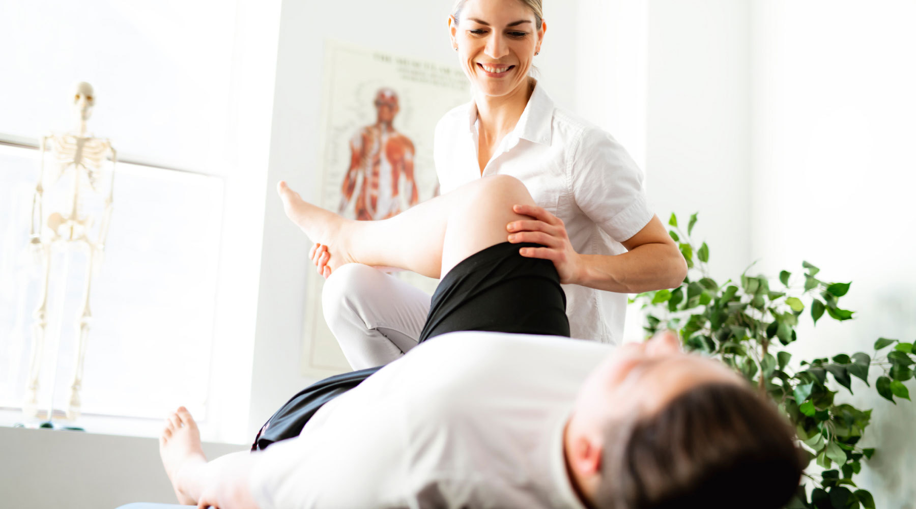 Medical professional helps patient stretch and analyze knee function.